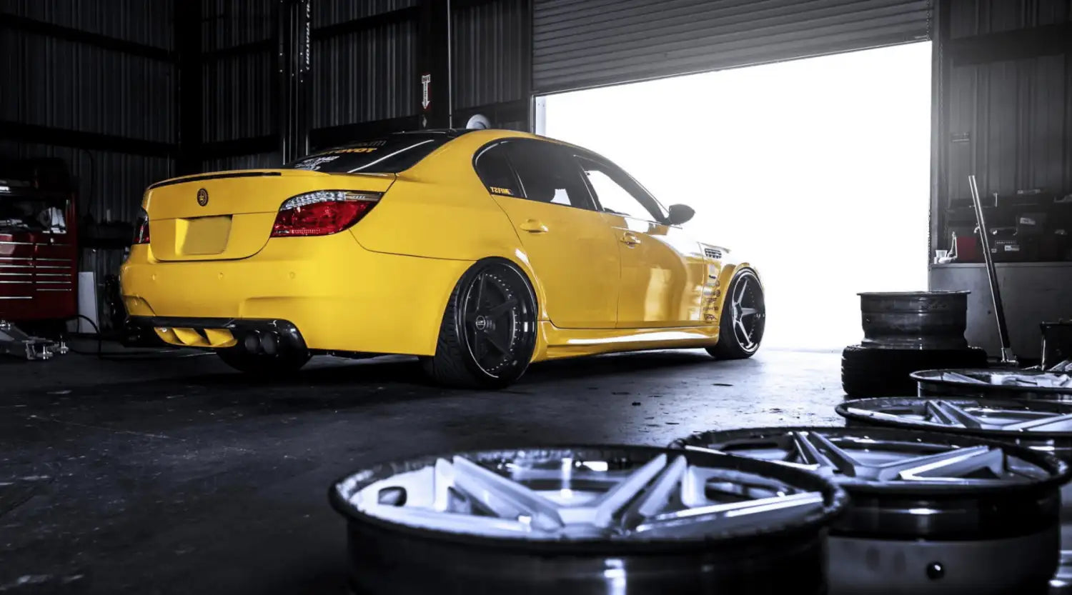 Berline BMW M5 2013 jaune avec jantes noires et accents en fibre de carbone.